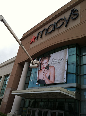 bucket lift being used to hand a department store window banner at Macys